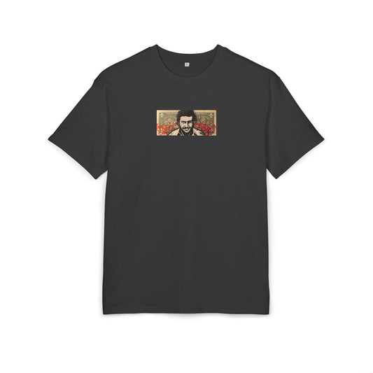 Black t-shirt with a small graphic dollar desing of pablo escobar on the chest against a white background, front